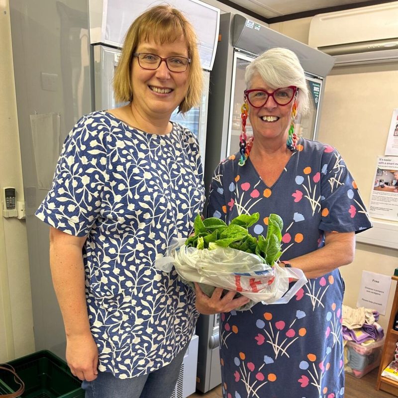 Two ladies holding food and smiling at the camera