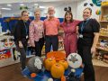 Five members of the Citizens Advice team stand in front of a table of Halloween decorations.